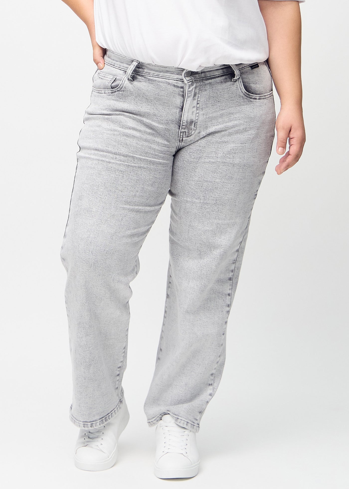 Lysegrå denim loose jeans, modelnavn Ashes, som er løstsiddende med masser af vidde i benene på en plus-size model, set forfra.