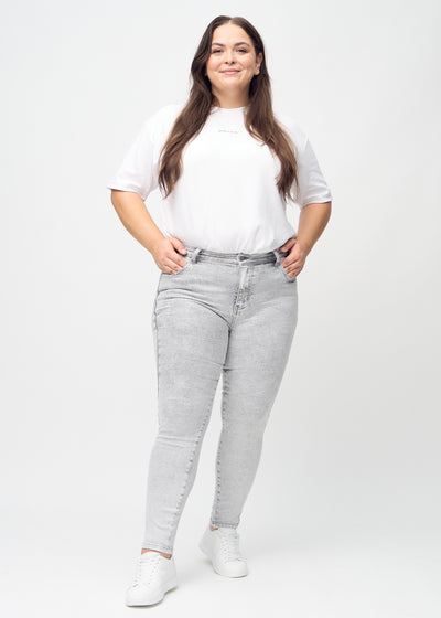 Fuldt billede af en plus-size model i lysegrå denim skinny jeans.