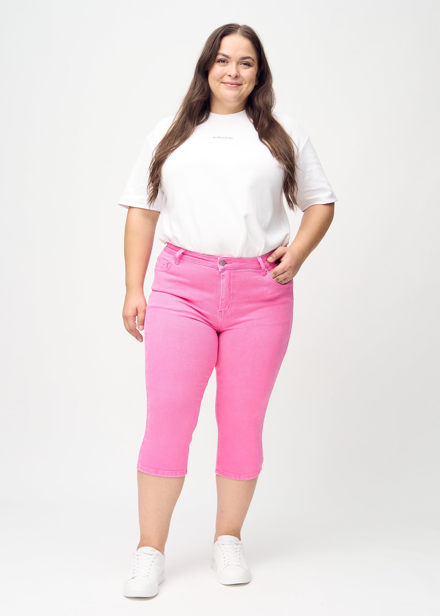 Fuldt billede af en plus-size model i lyserøde skinny capris.