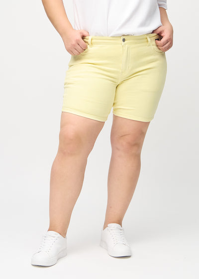 Lysegule skinny short shorts, modelnavn Lemonades, som sidder tæt til, og slutter midt på låret på en plus-size model, set forfra.