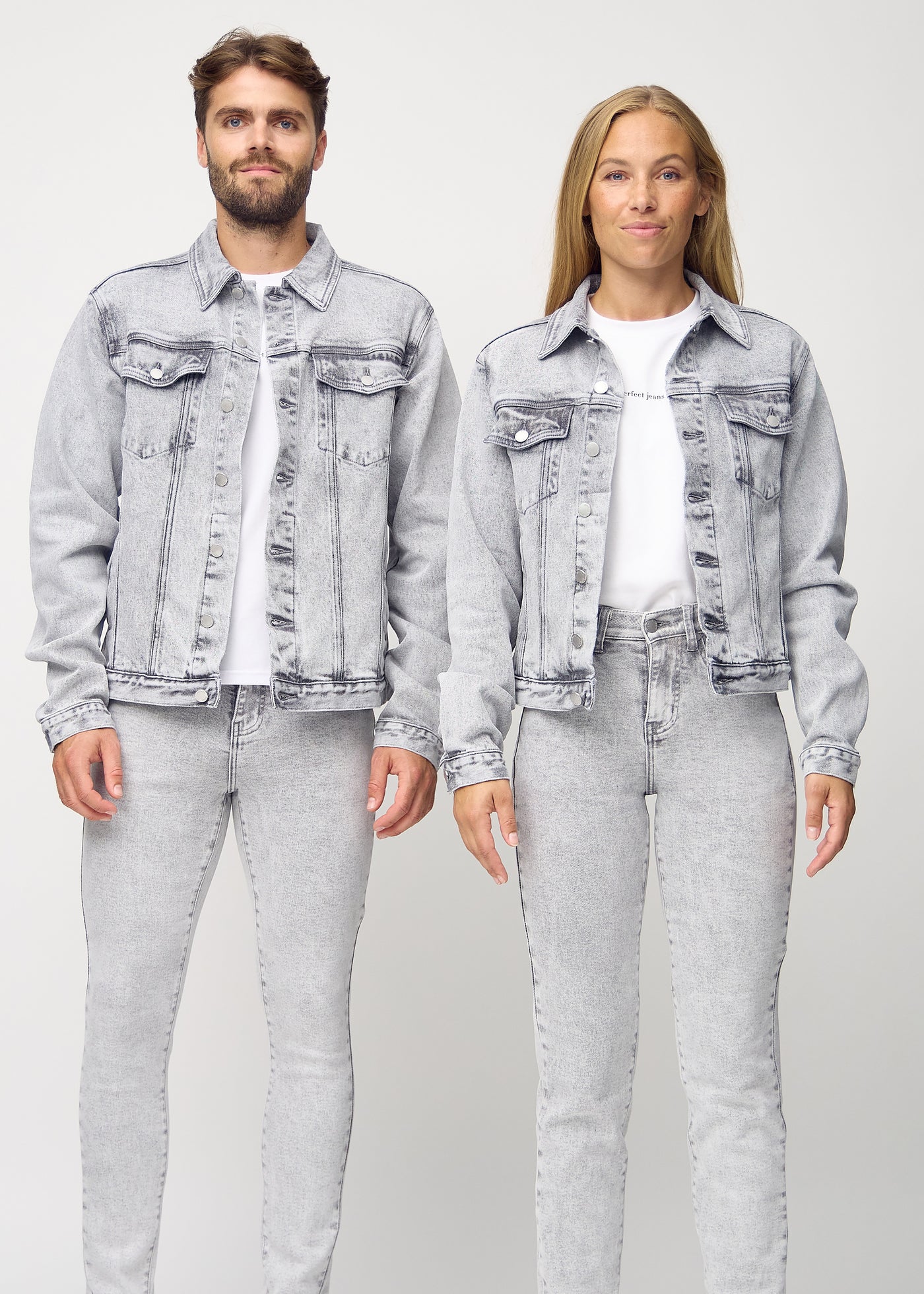 Unisex lysegrå denim jakke set forfra på herre- og damemodel, viser klassisk design med lige snit og knapper langs fronten. Jakken er i farven Ashes.